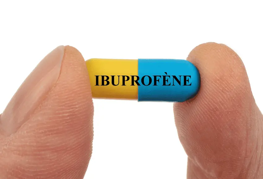 Fingers holding an ibuprofen capsule, relevant to the question: is ibuprofen safe for dogs?